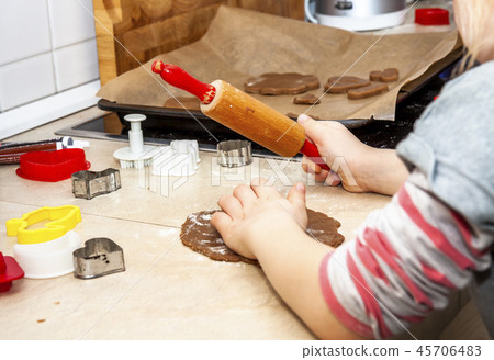 Little girl preparing a dough standing in the kitchen Little girl preparing a dough standing in the kitchen 45706483