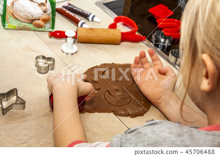 Little girl preparing a dough standing in the kitchen 45706488