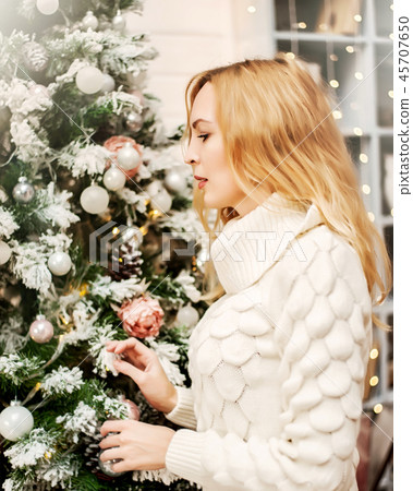 woman in white sweater stands near a Christmas tree woman in white sweater stands near a Christmas tree 45707650