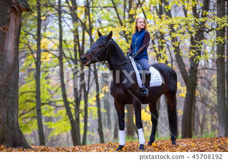 Teenage girl riding horse in autumn park Teenage girl riding horse in autumn park 45708192