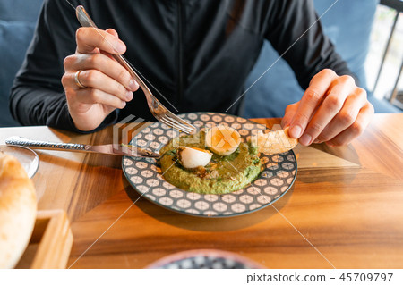 Close-up of a man having lunch. Hummus with nuts and boiled egg and olive oil. It is served in the 45709797