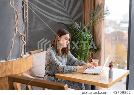 Young woman Typing on the keyboard, chatting, maintains a blog. Freelancer work on netbook in modern 45709862