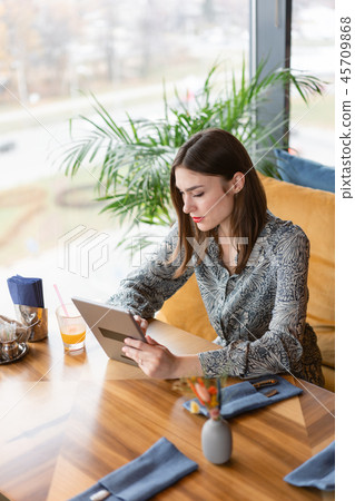 Young woman Typing on tablet, chatting, maintains a blog. Freelancer work in cafe modern coworking Young woman Typing on tablet, chatting, maintains a blog. Freelancer work in cafe modern coworking 45709868