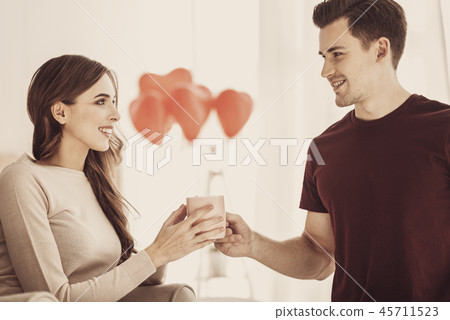 Attentive caring boyfriend giving cup of coffee to his fiance Attentive caring boyfriend giving cup of coffee to his fiance 45711523