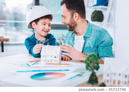 Smiling son and dad making a paper figure together Smiling son and dad making a paper figure together 45715740