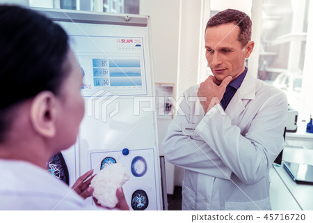Attentive brunette man staring at model of brains 45716720