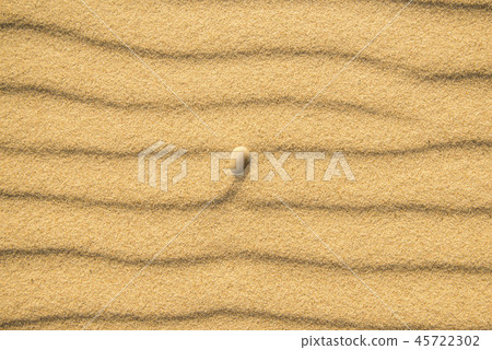 Sand of a beach with pebble and wave patterns 45722302