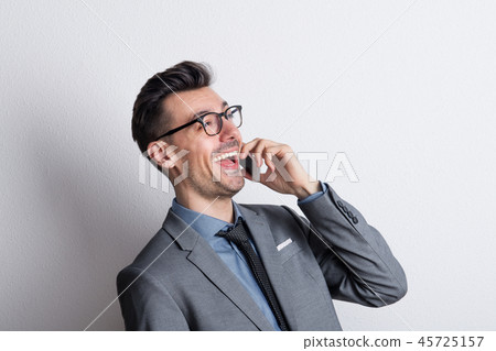 Portrait of a young lauhing man with a smartphone in a studio. 45725157