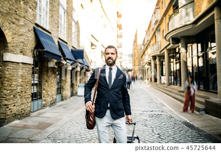 Hipster businessman with suitcase walking down the street in London. 45725644