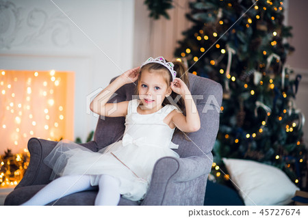 Pretty little girl sitting in the armchair. Magic and festive atmosphere. 45727674