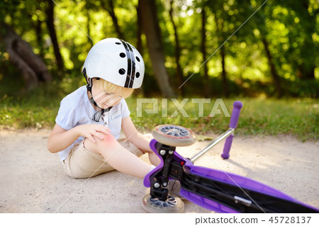 Toddler boy learning to ride scooter Toddler boy learning to ride scooter 45728137