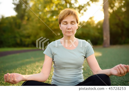 Mature woman practicing yoga outdoor  45728253