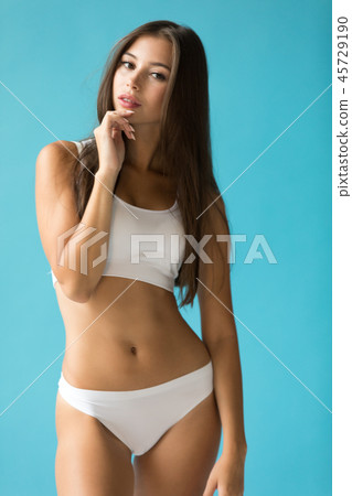 Attractive young woman in white sport underwear on a blue background. Attractive young woman in white sport underwear on a blue background. 45729190