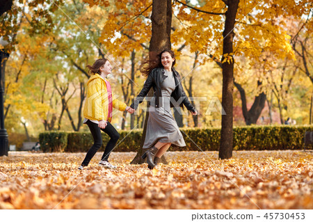Two happy girls running in autumn city park. 45730453