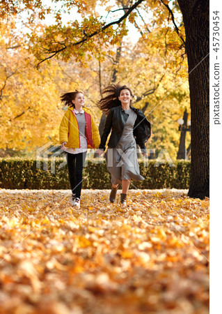 Two happy girls running in autumn city park. 45730454