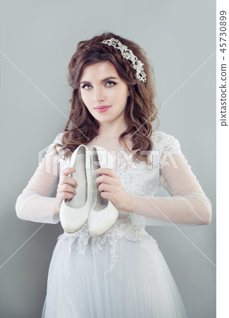 Beautiful bride woman holding white bridal shoes 45730899