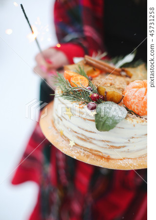 young woman holding a christmas cake in the street. it's snowing, sparkler young woman holding a christmas cake in the street. it's snowing, sparkler 45731258
