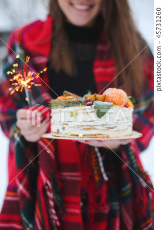young woman holding a christmas cake in the street. it's snowing, sparkler young woman holding a christmas cake in the street. it's snowing, sparkler 45731260