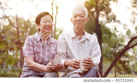 Casual Asian couple drinking tea in morning garden Casual Asian couple drinking tea in morning garden 45731841