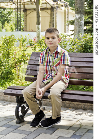 Cute brunette boy are sitting on the bench 45733590