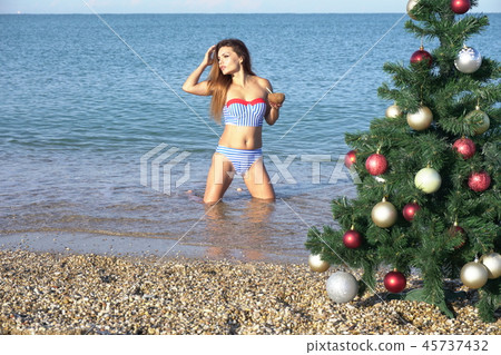 a beautiful woman in a swimsuit sea Christmas new year tree vacation 45737432
