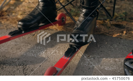 Training an athlete on the roller skaters. Biathlon ride on the roller skis with ski poles, in the Training an athlete on the roller skaters. Biathlon ride on the roller skis with ski poles, in the 45750076