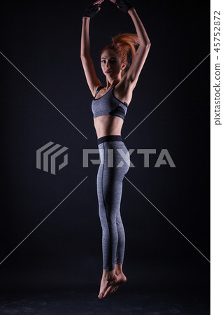 Fitness girl doing jumping pose while she's at a studio photoshoot. 45752872
