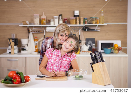 Mother and daughter joking around while they cook together Mother and daughter joking around while they cook together 45753087