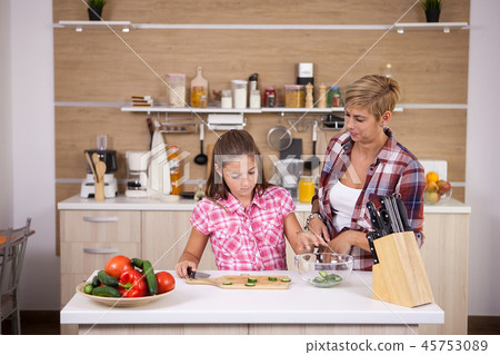 Teenage girl and her mother making healthy food for dinner Teenage girl and her mother making healthy food for dinner 45753089