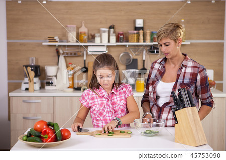 Teenage girl and her mother making healthy food for dinner Teenage girl and her mother making healthy food for dinner 45753090