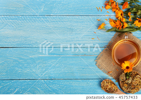 Calendula tea with fresh and dried flowers on blue wooden background with copy space for your text Calendula tea with fresh and dried flowers on blue wooden background with copy space for your text 45757433
