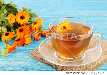 Calendula tea with fresh flowers on blue wooden background Calendula tea with fresh flowers on blue wooden background 45757434