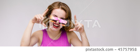 Charming young girl in pink dress on gray background. Cheerful girl in square glasses. The girl 45757958