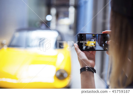 Hand holding phone mobile and takes pictures of a car Hand holding phone mobile and takes pictures of a car 45759187