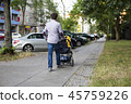 Young dad walking with a baby carriage on sidewalk 45759226