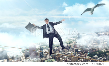 Businessman walking on a rope over business center 45760719