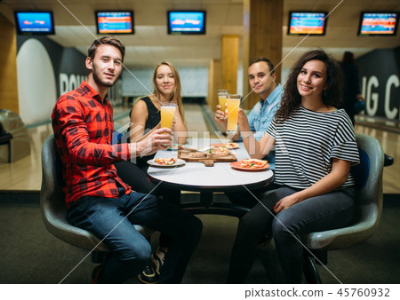 Friends drinks and eats pizza in bowling club 45760932