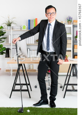 Businessman practicing golf in office. 45768367