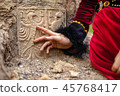lady in historic dress beside heraldic sign carved in stone. 45768417