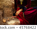 lady in historic dress beside heraldic sign carved in stone. 45768422