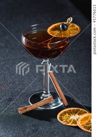 The Boulevardier Cocktail with orange chips on top. On a bar desk 45776013