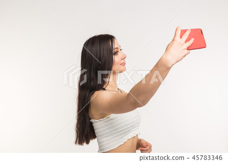 Happy european female model with dark hair enjoying indoor photoshoot. Young woman is taking a Happy european female model with dark hair enjoying indoor photoshoot. Young woman is taking a 45783346