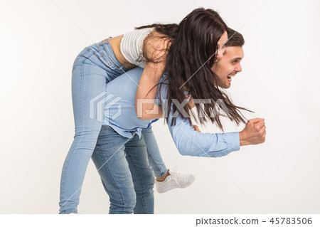 Young male carrying his girlfriend piggyback. They are fooling around Young male carrying his girlfriend piggyback. They are fooling around 45783506