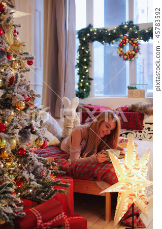 young woman in christmas interior. Sit with a plaid and a cup of tea. 45783592