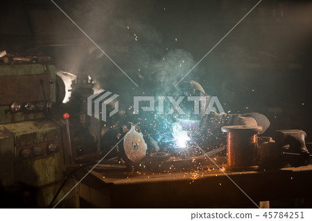 Welder is welding metal part in factory 45784251