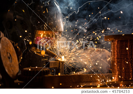 Welder is welding metal part in factory 45784253