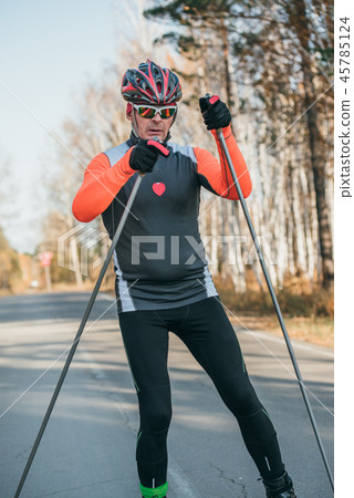 Training an athlete on the roller skaters. Biathlon ride on the roller skis with ski poles, in the 45785124