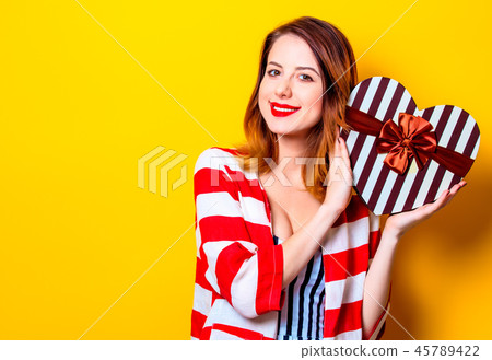 Woman with heart shape box on yellow background Woman with heart shape box on yellow background 45789422