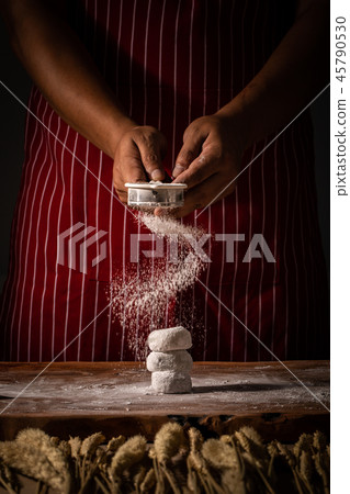 Chef spreading flour on bakery. Chef spreading flour on bakery. 45790530