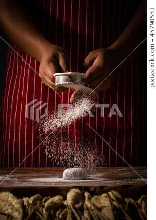 Chef spreading flour on bakery. Chef spreading flour on bakery. 45790531
